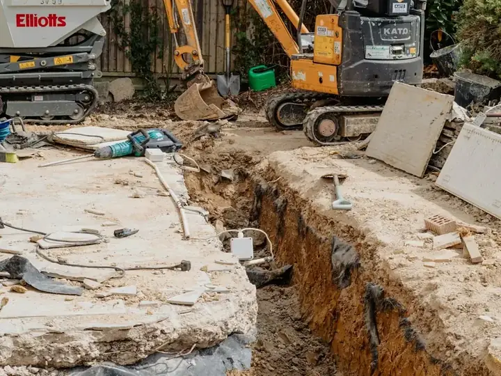 Tranchée ouverte le long d’une maison, mini-pelle en arrière-plan
